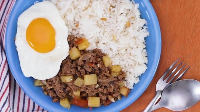 pork giniling with potatoes on a blue plate with garlic rice and sunny side up egg