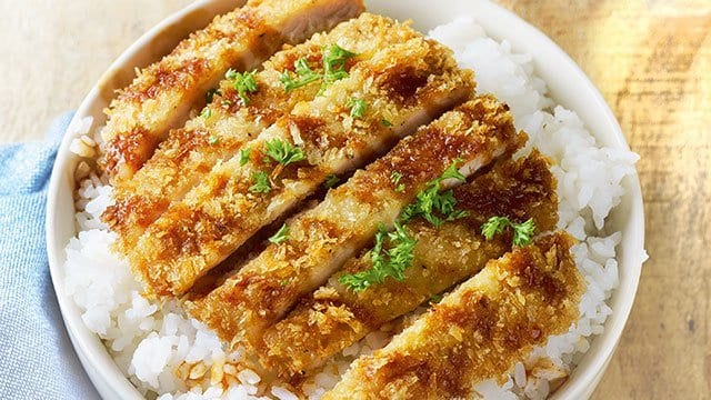pork tonkatsu drizzled with tonkatsu sauce, over a bed of rice