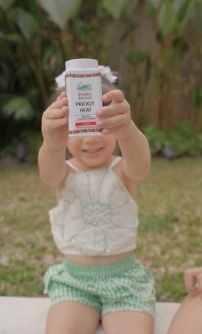 Kid holding Snake Brand Prickly Heat powder