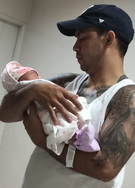 dad with tattoos cradling baby