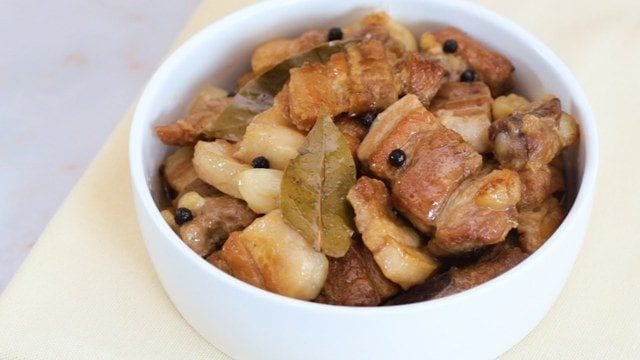 adobong puti with bay leaves and whole black peppercorns in a white bowl