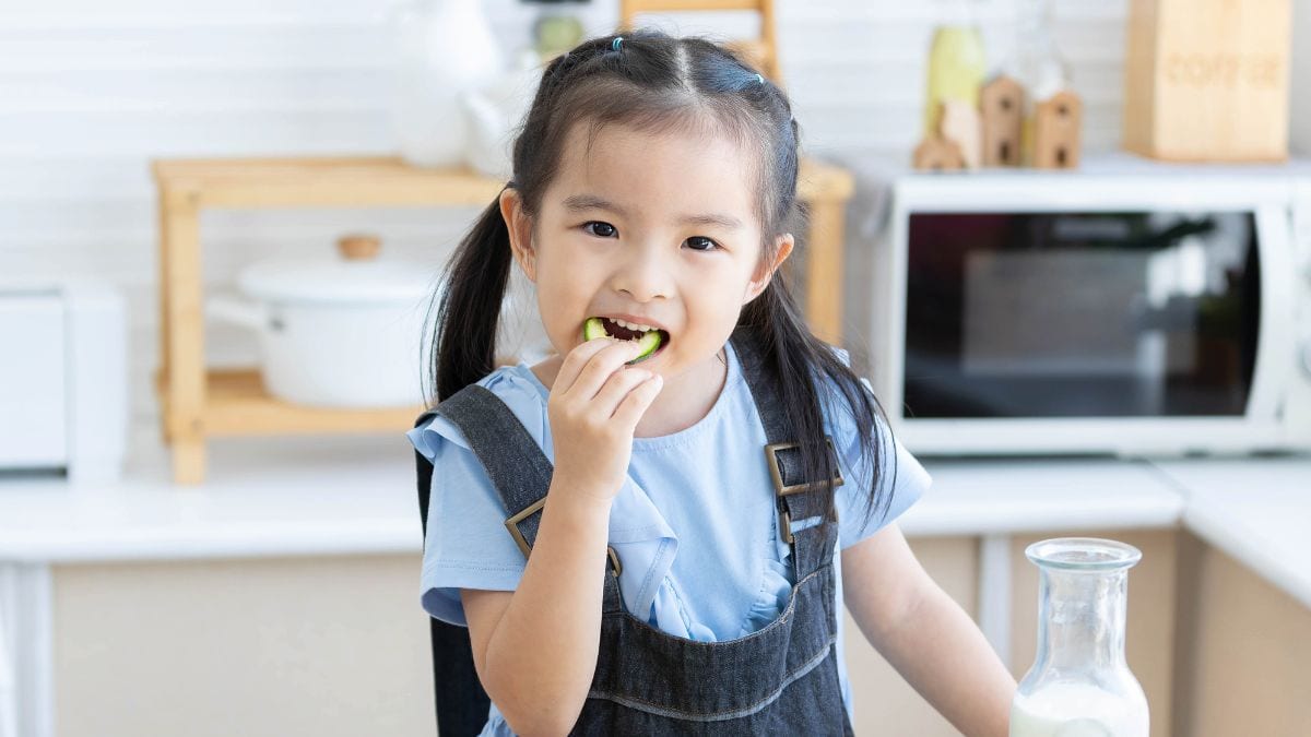 cute asian girl eating a cucumber slice