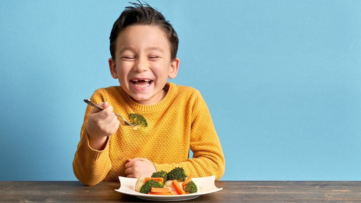 kid eating broccoli happily