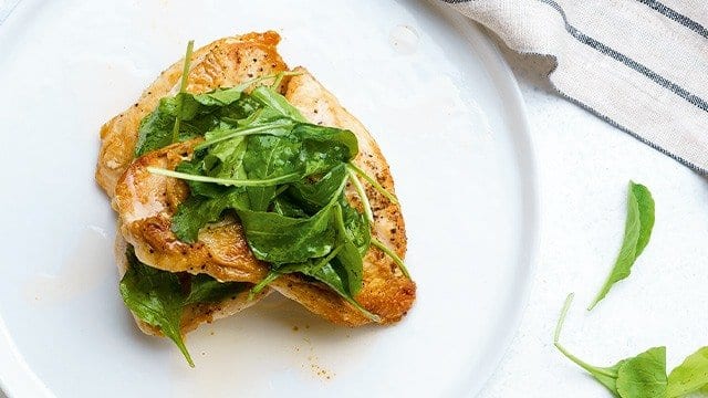 Boneless Fried Chicken on a white plate, topped with arugula