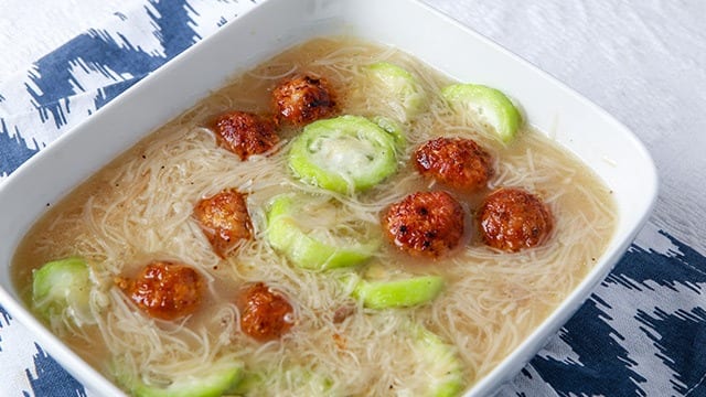 almondigas soup in a white bowl with meatballs and patola