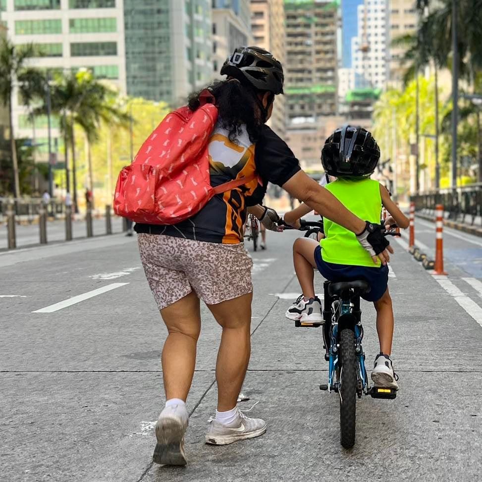 A child learning to ride a bike together with their guardian.